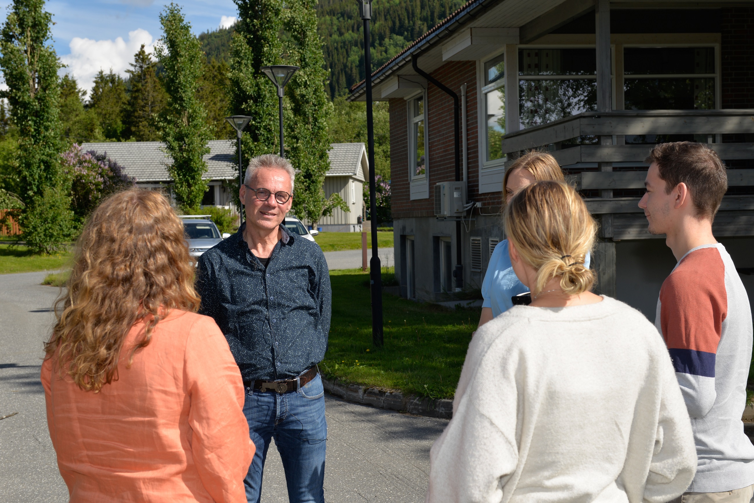 Flere kolleger står ute i sola og snakker sammen