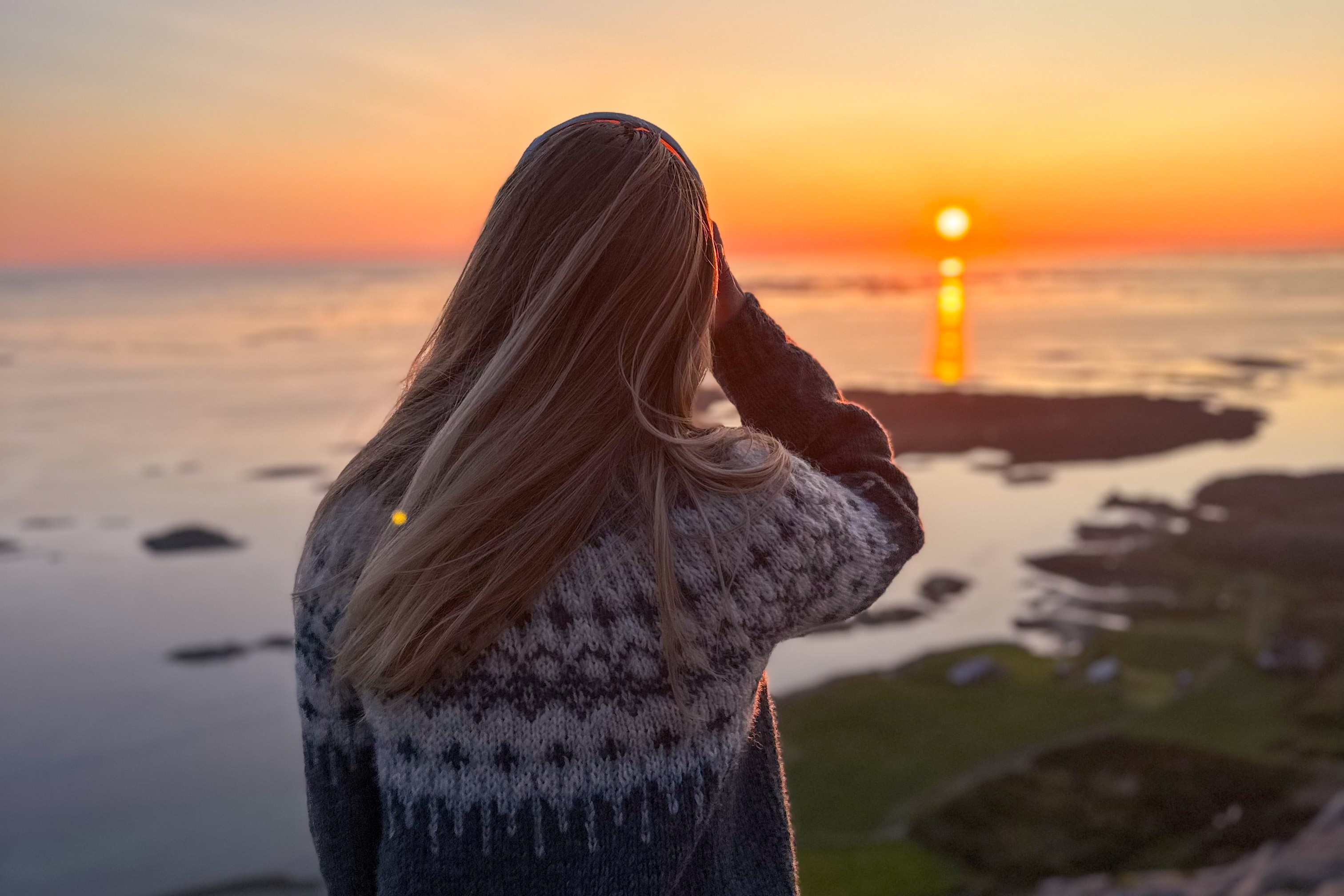 dame som speider utover blankstille hav i solnedgang