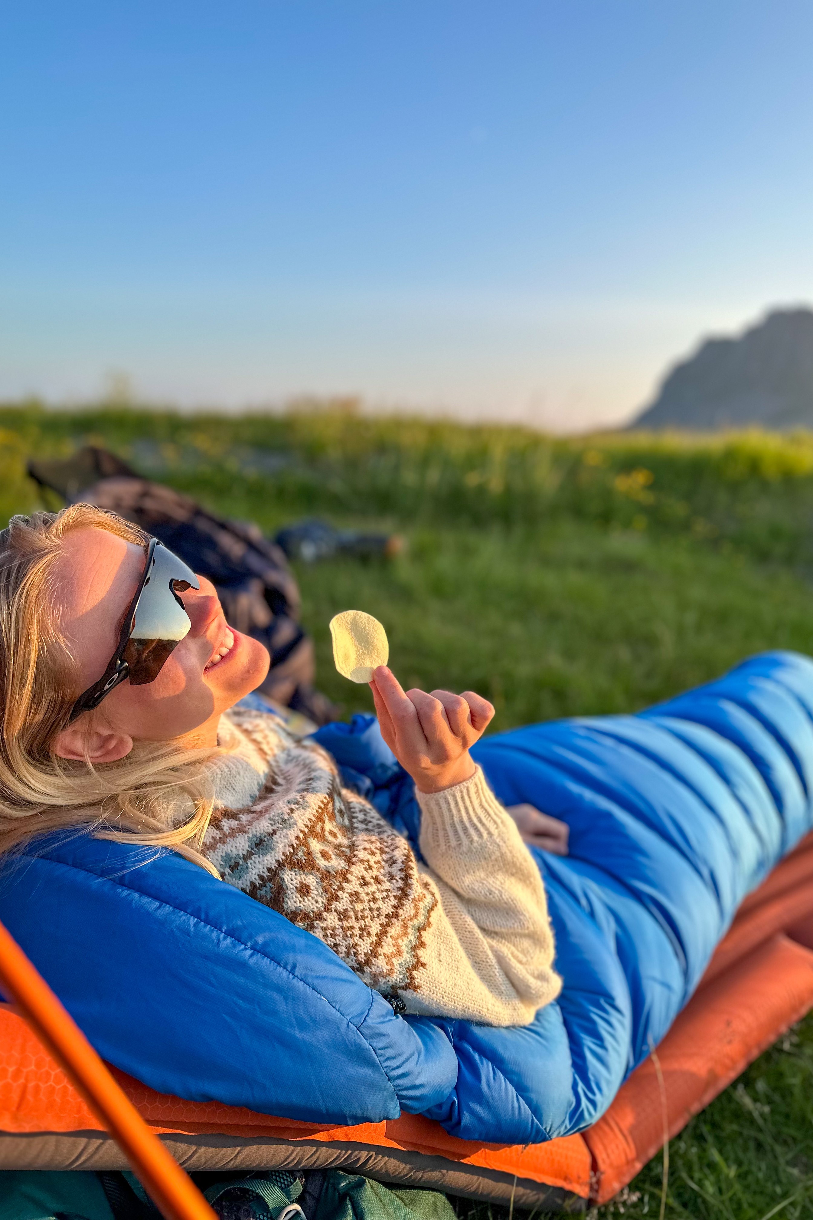 Dame som sitter i soveposen og nyter naturen