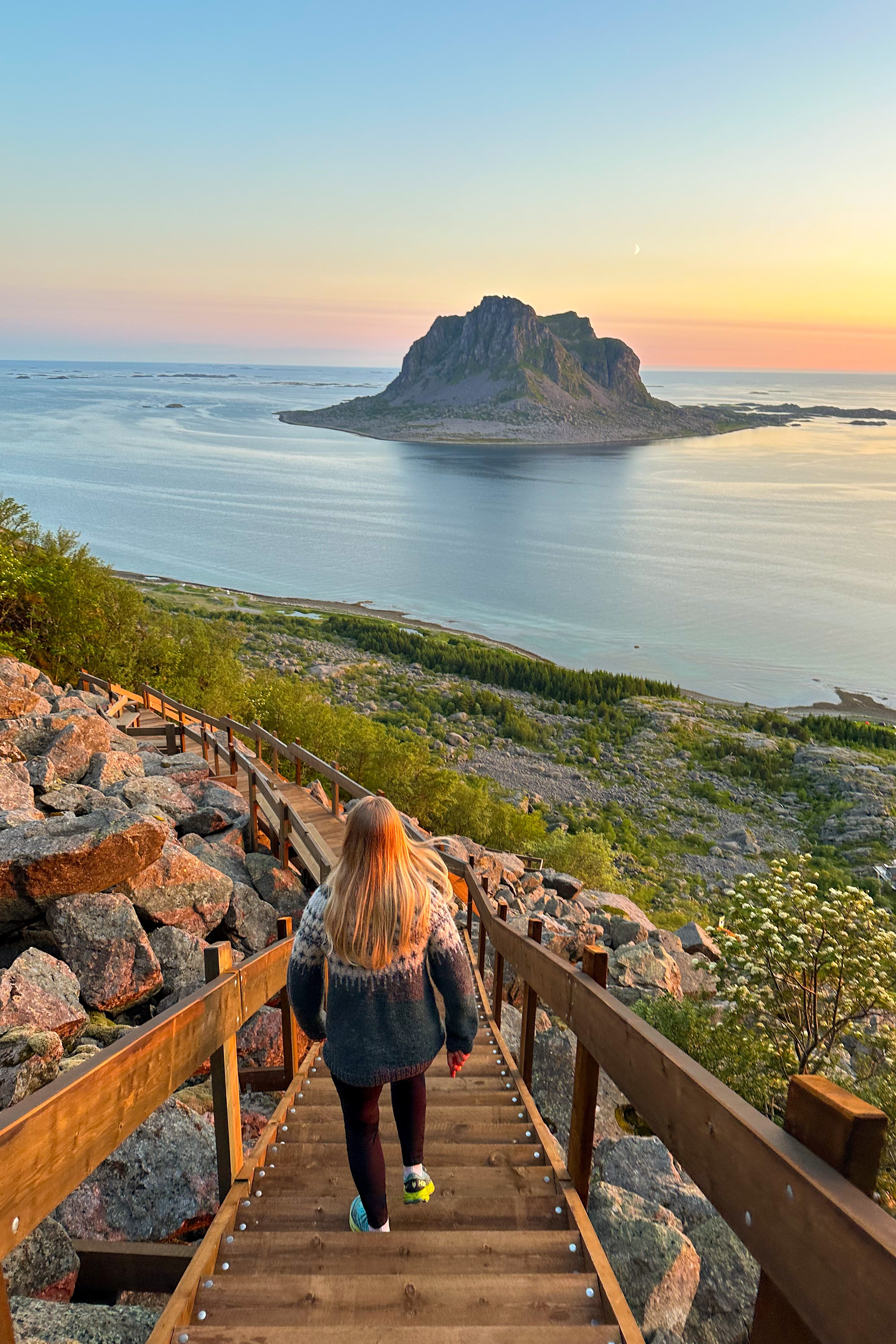 Dame som går ned en tretrapp med utsikt utover havet